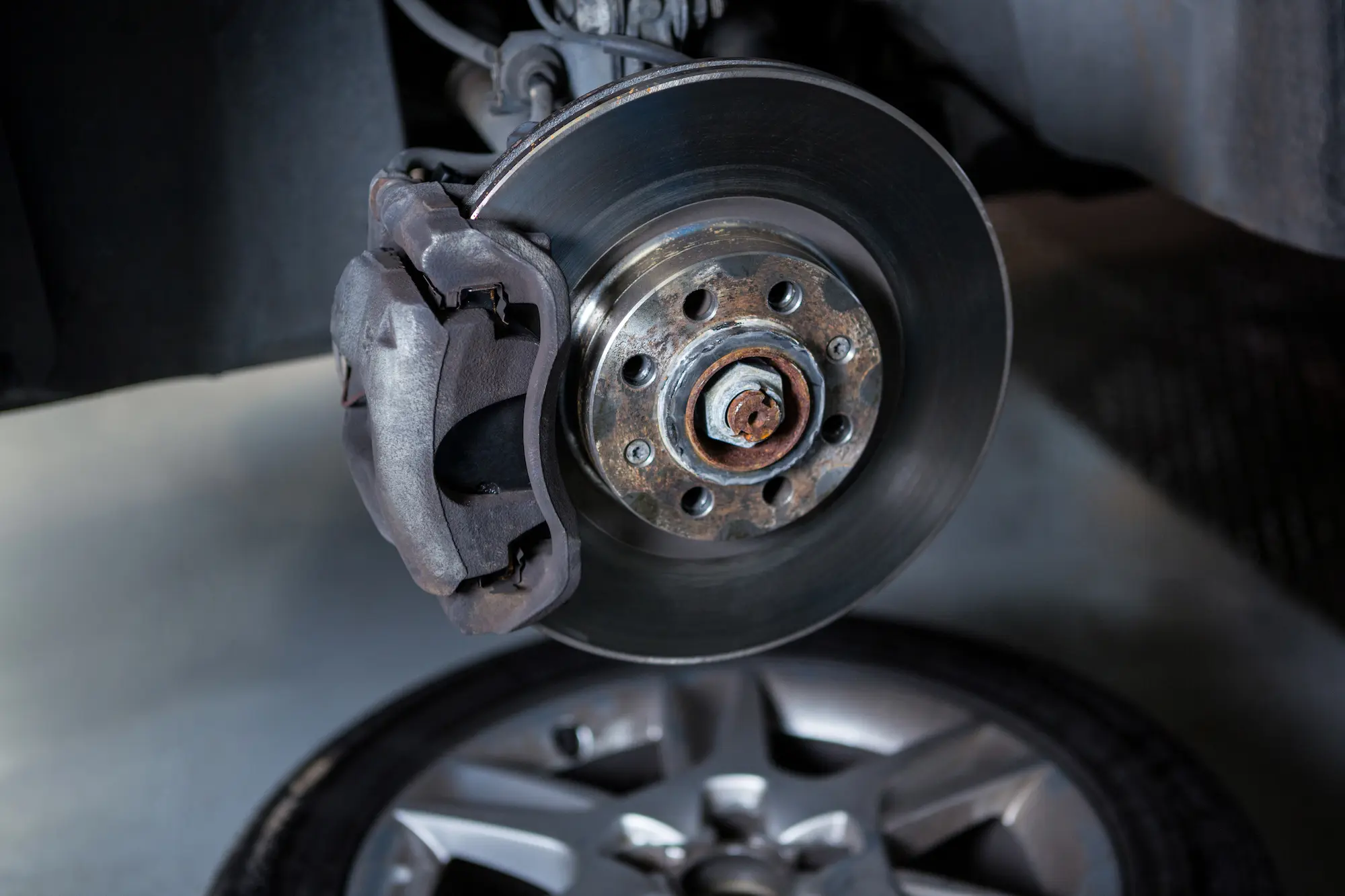 Close-up of a car brake disc and caliper during a brake inspection at an auto repair workshop